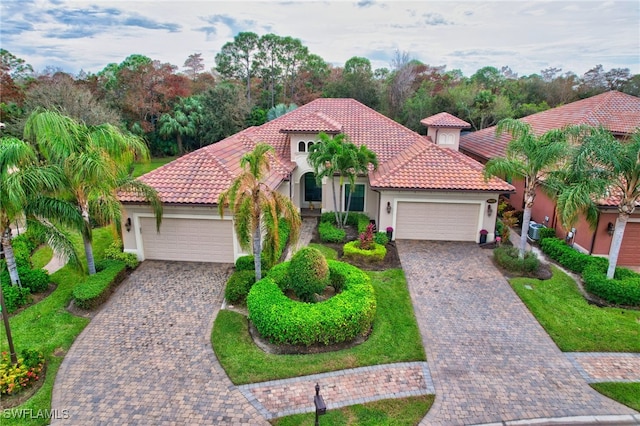 mediterranean / spanish house featuring central AC, a garage, and a front lawn