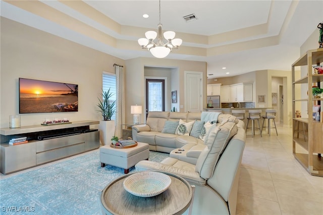 living room with a raised ceiling, light tile patterned floors, and a chandelier