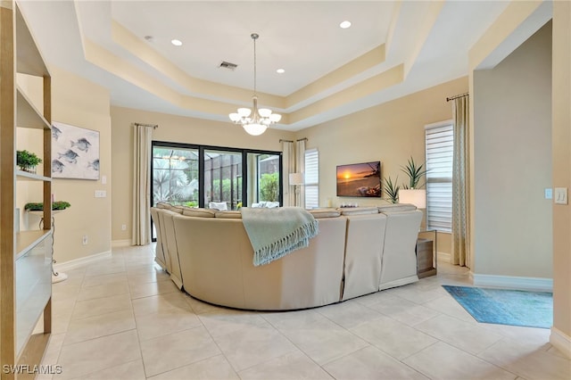 living room featuring a chandelier, a tray ceiling, and light tile patterned floors