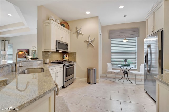 kitchen with light stone countertops, appliances with stainless steel finishes, sink, decorative light fixtures, and light tile patterned floors