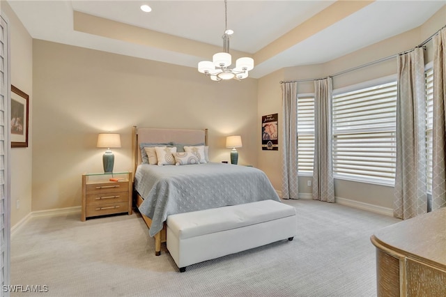 carpeted bedroom with a tray ceiling and a chandelier