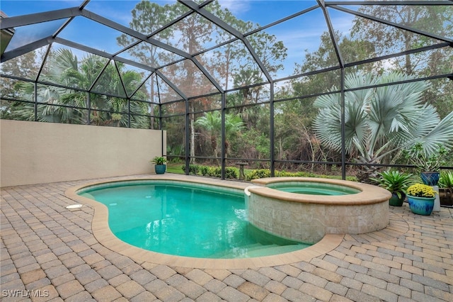 view of pool with an in ground hot tub, a patio area, and glass enclosure