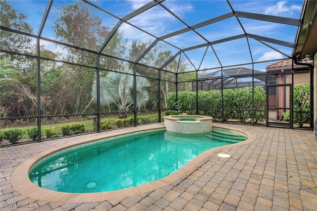 view of pool featuring an in ground hot tub, a patio area, and glass enclosure