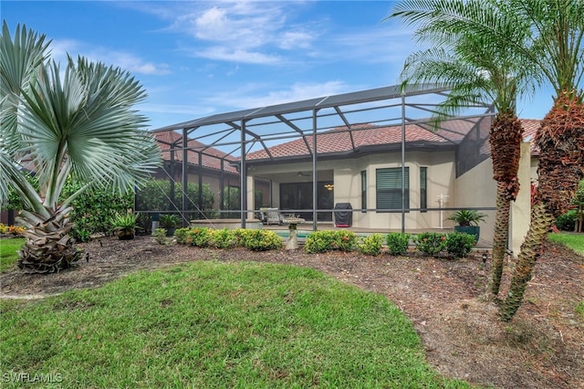 back of property featuring a lawn, a patio area, and glass enclosure