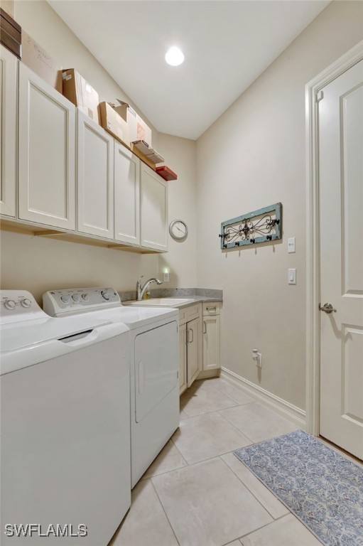 clothes washing area with light tile patterned flooring, cabinets, sink, and washer and clothes dryer