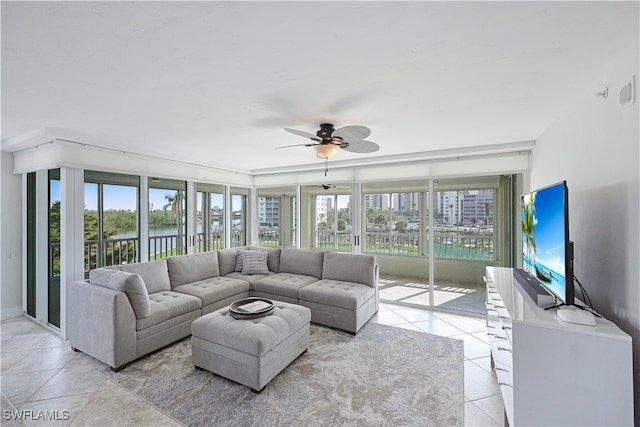 tiled living room with ceiling fan, plenty of natural light, and a water view