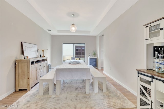 dining room with a tray ceiling and light hardwood / wood-style floors