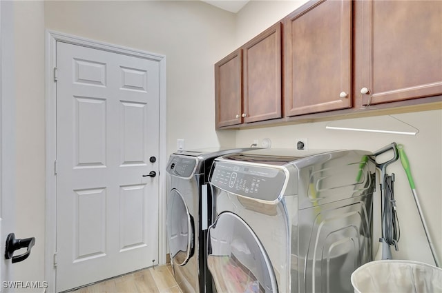 washroom featuring cabinets, washing machine and dryer, and light hardwood / wood-style floors