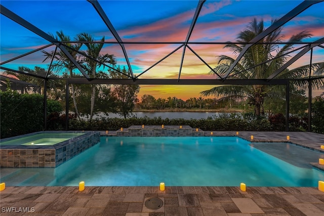 pool at dusk with an in ground hot tub, a water view, and glass enclosure