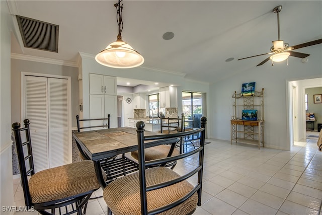 dining space featuring sink, ceiling fan, vaulted ceiling, crown molding, and light tile patterned floors