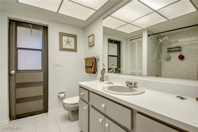 bathroom featuring vanity, toilet, tile patterned floors, and tiled shower