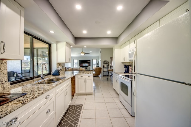 kitchen with white appliances, tasteful backsplash, kitchen peninsula, white cabinets, and light tile patterned floors