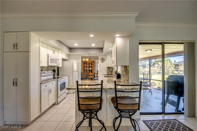 kitchen with backsplash, white cabinets, light stone countertops, and white appliances