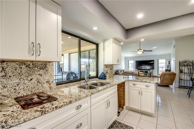 kitchen with kitchen peninsula, white cabinets, tasteful backsplash, and sink