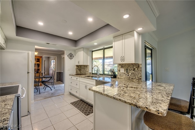 kitchen featuring stainless steel range, kitchen peninsula, white cabinets, and a breakfast bar area