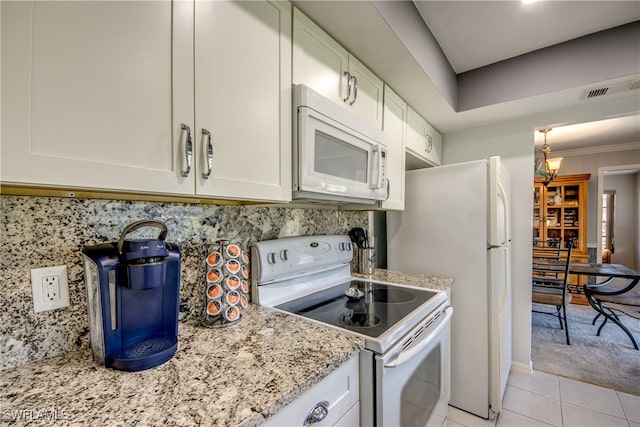 kitchen with white cabinets, light stone countertops, ornamental molding, light tile patterned flooring, and white appliances