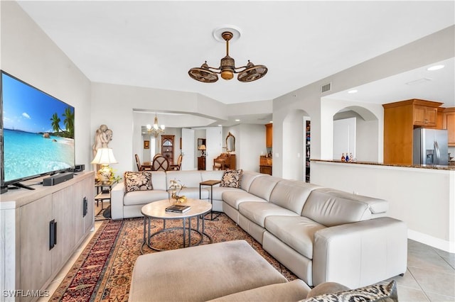 living room featuring ceiling fan with notable chandelier and light tile patterned floors