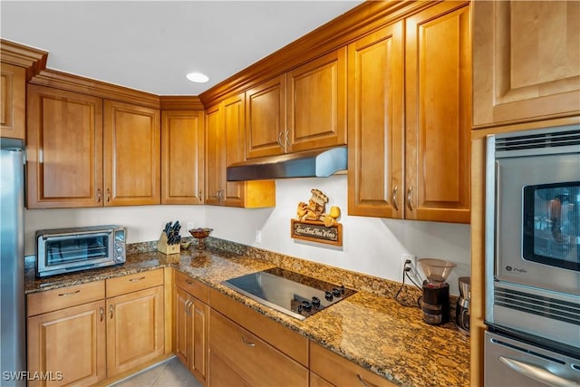 kitchen with appliances with stainless steel finishes, dark stone counters, and light tile patterned flooring