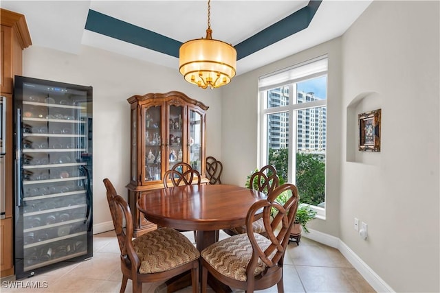 tiled dining room with beverage cooler and a tray ceiling