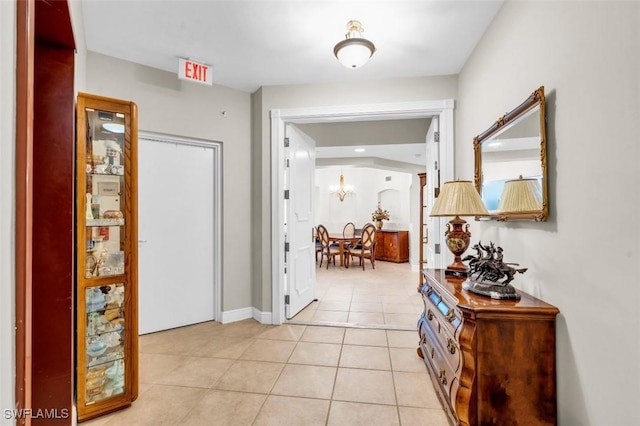 corridor featuring light tile patterned floors and a notable chandelier