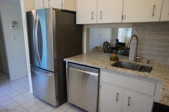 kitchen with tasteful backsplash, sink, stainless steel appliances, light stone counters, and light tile patterned floors