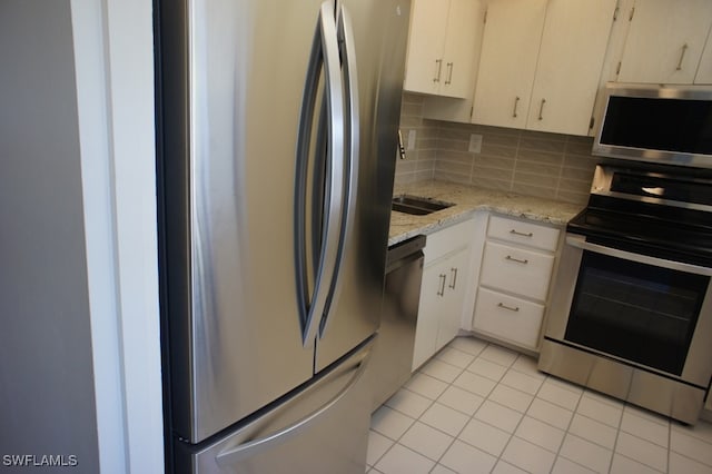 kitchen featuring light stone countertops, stainless steel appliances, light tile patterned floors, and tasteful backsplash