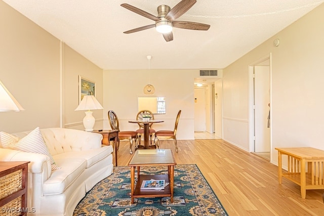 living room featuring a textured ceiling, wood-type flooring, and ceiling fan