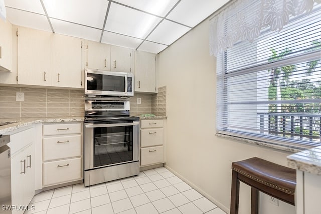 kitchen featuring white cabinetry, stainless steel appliances, decorative backsplash, and light tile patterned flooring