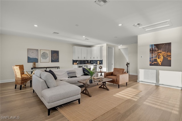 living room with recessed lighting, visible vents, baseboards, and light wood-style floors