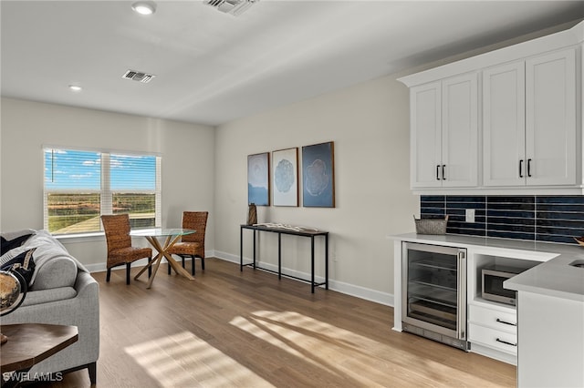 bar with wine cooler, visible vents, and baseboards