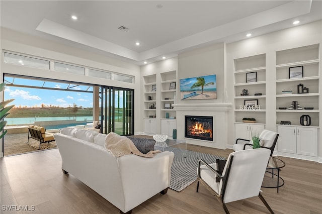 living room featuring recessed lighting, wood finished floors, built in shelves, and a glass covered fireplace