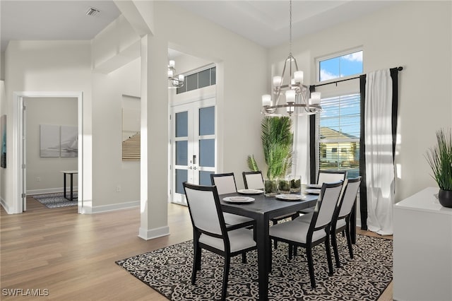dining area with a chandelier, french doors, visible vents, baseboards, and wood finished floors