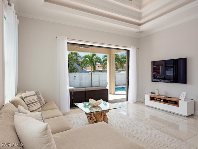 tiled living room with crown molding, a raised ceiling, and ceiling fan