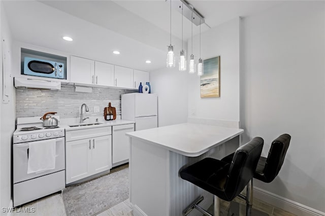 kitchen featuring a kitchen breakfast bar, ventilation hood, sink, white cabinets, and white appliances