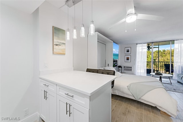 bedroom with access to exterior, ceiling fan, a wall unit AC, floor to ceiling windows, and light hardwood / wood-style flooring