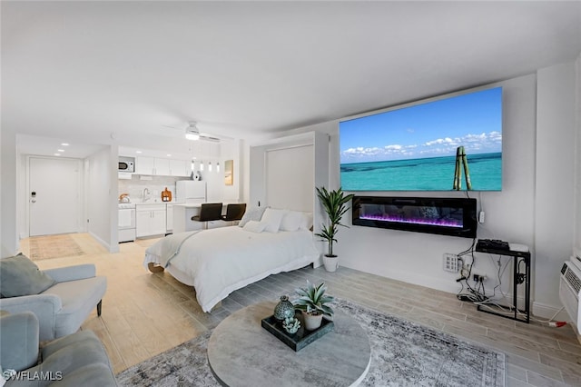 bedroom with white refrigerator, separate washer and dryer, light wood-type flooring, and ceiling fan
