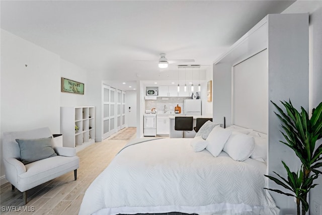 bedroom featuring white fridge, light hardwood / wood-style floors, and ceiling fan