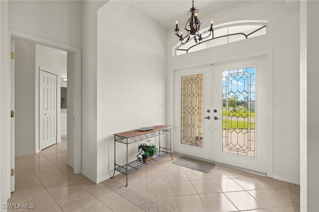 foyer entrance featuring french doors, light tile patterned flooring, and an inviting chandelier