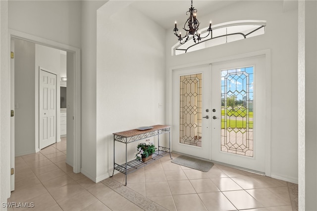 foyer with an inviting chandelier, a high ceiling, baseboards, and light tile patterned floors