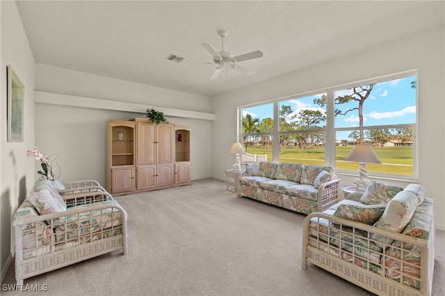 living area featuring ceiling fan, visible vents, and light carpet