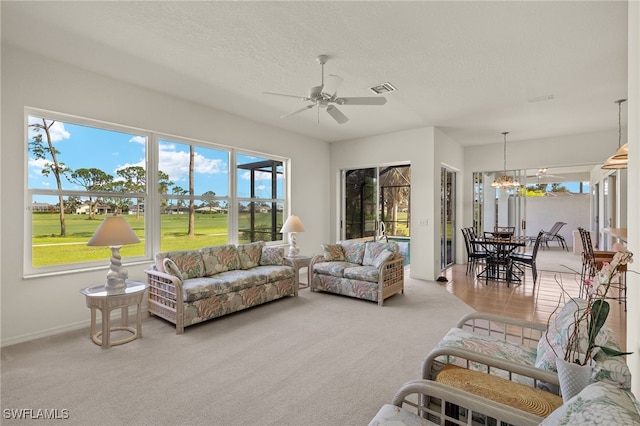 carpeted living room featuring a textured ceiling and ceiling fan with notable chandelier