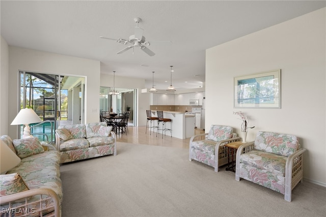living area with baseboards, ceiling fan, and light carpet