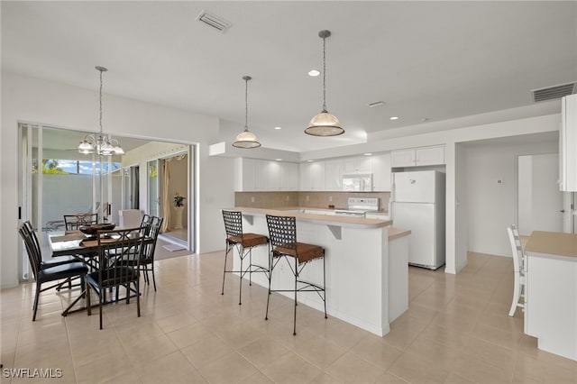 kitchen with decorative backsplash, light countertops, a breakfast bar, white appliances, and white cabinetry
