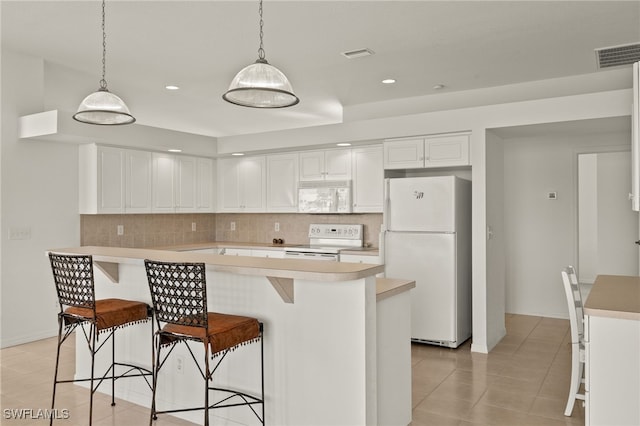 kitchen featuring visible vents, light countertops, decorative backsplash, and white appliances