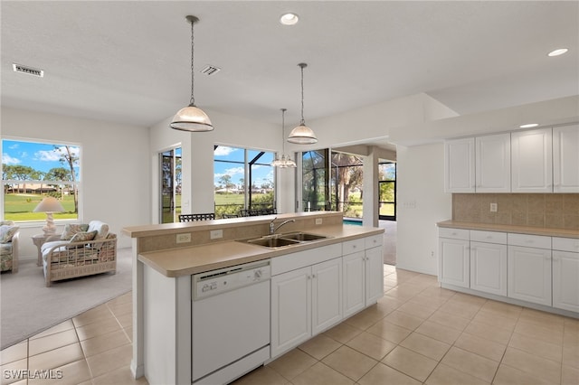 kitchen with hanging light fixtures, white dishwasher, a center island with sink, sink, and white cabinetry