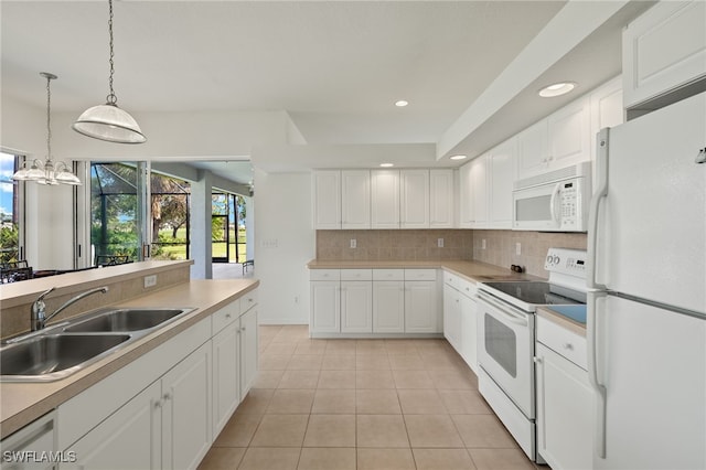 kitchen with white appliances, light tile patterned flooring, sink, white cabinets, and a notable chandelier