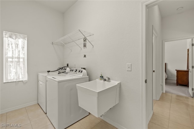 clothes washing area with laundry area, a sink, light tile patterned floors, and separate washer and dryer