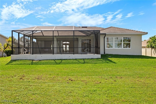 rear view of property featuring a lawn, a tile roof, glass enclosure, and stucco siding