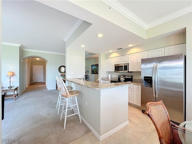 kitchen with light stone counters, white cabinetry, appliances with stainless steel finishes, light carpet, and kitchen peninsula