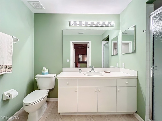 bathroom featuring toilet, vanity, tile patterned floors, and a shower with door